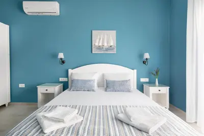 a blue bedroom with a white bed with two pillows at Evi Boutique Rooms in Galatás