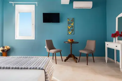 a bedroom with blue walls and two chairs and a table at Evi Boutique Rooms in Galatás