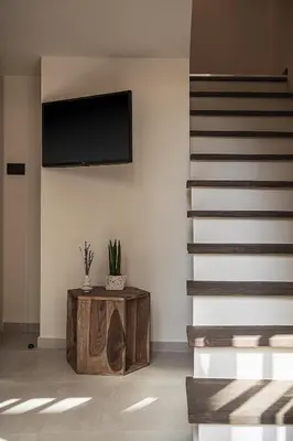 a living room with a staircase and a tv on a wall at Copal Experience The Port in Chania Town