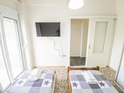 two beds in a room with a tv on the wall at Fully renovated apartment close to the bus station and the city center! in Chania Town