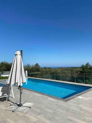 an umbrella and a chair next to a swimming pool at Villa Panorama Modi, with pool and stunning views in Chania Town