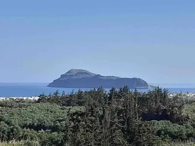 an island in the water with trees in the foreground at Villa Panorama Modi, with pool and stunning views in Chania Town