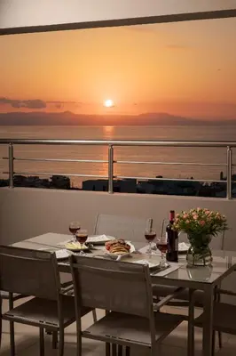 a table with wine glasses on a balcony with the sunset at Overview Chania with sea view and amazing sunset in Chania Town