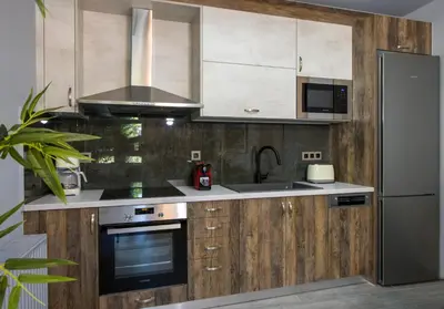 a kitchen with wooden cabinets and a stainless steel refrigerator at Rena's luxury apartment with free private parking in Chania Town