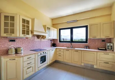 a large kitchen with white cabinets and a window at Fotini 's apartment near the city center. in Chania Town