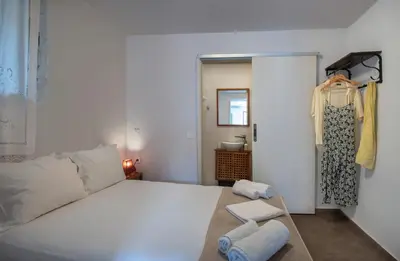 a bedroom with a large white bed and two towels at Feneri 3 -Cozy rustic Apt 20' from Elafonisi beach in Elafonisi