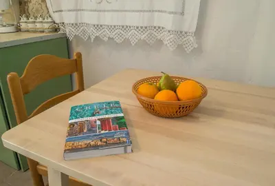 a table with a bowl of oranges and a book at Feneri 3 -Cozy rustic Apt 20' from Elafonisi beach in Elafonisi