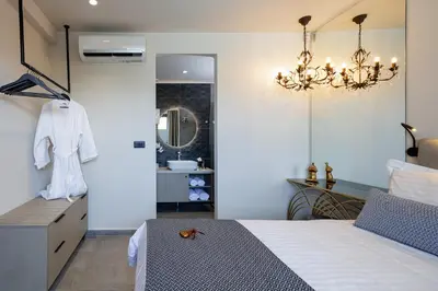 a bedroom with a bed and a sink and a chandelier at VillAgioi - Luxury villas, Private Pools, 450m to the Beach in Chania Town