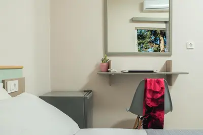 a bedroom with a bed and a mirror and a chair at Stefanie Studios in Agia Marina Nea Kydonias