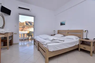 a bedroom with a bed and a desk and a mirror at PALEOCHORA FINIKAS Apartments in Palaiochóra