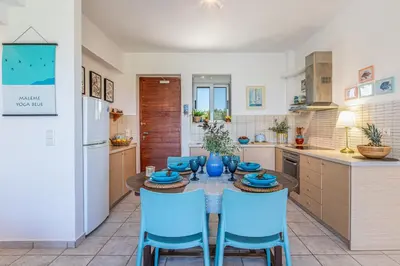 a kitchen with a table and blue chairs in a kitchen at Maleme Yoga Blue in Chania Town
