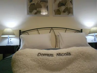 a bed with a white comforter with the words dominis métops at Domus Nicola in Chania Town