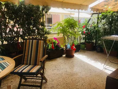 a patio with a chair and potted plants and a table at At the Beach! +10min= port&center. in Chania Town