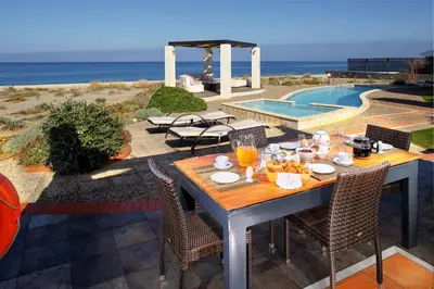 a table with food and drinks on it next to a pool at Beachfront villa Aqua Marine with private pool,ping-pong & BBQ in Chania Town