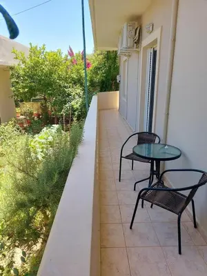 a patio with two chairs and a table on a building at Chrissoula House In Agioi Apostoloi in Daratso