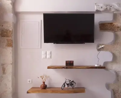a television on a wall with a bike on a shelf at Ariadne Luxury Home in Chania Town