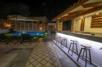 a patio with stools and a swimming pool at night at Casa Christina-Luxury Villa in Kissamos