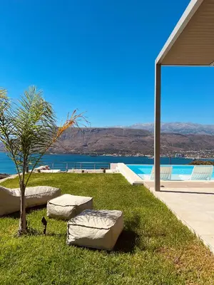 a house with a lawn with a tree and a pool at Bay Overlook Villa in Korakiaí