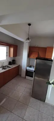 a kitchen with wooden cabinets and a stainless steel refrigerator at NickTheGreekApartment in Galatás