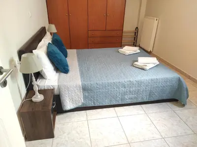 a bedroom with a bed with blue pillows and a table at NickTheGreekApartment in Galatás