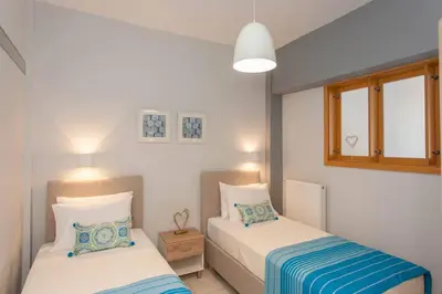 a bedroom with two beds and two windows at Neoria apartment in Chania Town