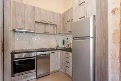 a kitchen with a stainless steel refrigerator and wooden cabinets at Casa Athelia: Traditional Home, Local Neighborhood in Chania Town