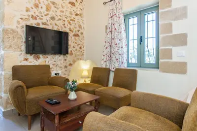 a living room with three chairs and a tv at Casa Athelia: Traditional Home, Local Neighborhood in Chania Town