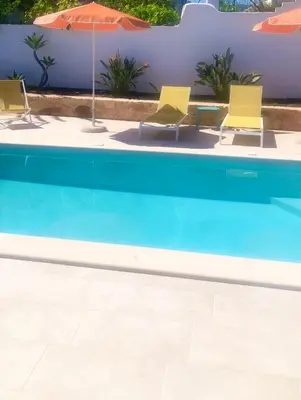 a group of chairs and umbrellas next to a swimming pool at Katikies Savrani in Perivólia