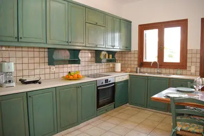 a green kitchen with green cabinets and a table at Rastoni Chania - Guests Apartment in Chania Town