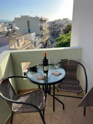 a table with two glasses and a bottle of wine on a balcony at Eteá Urban Nest living In the Heart of Chania in Chania Town
