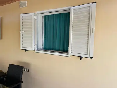 two windows in a room with a chair and a green curtain at Chania Casa Portokali in Perivólia