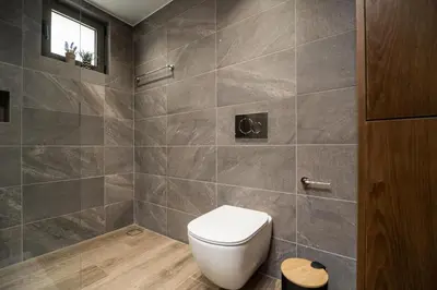 a bathroom with a toilet and a tiled wall at Amalthia Casa by 8essentially in Chania Town
