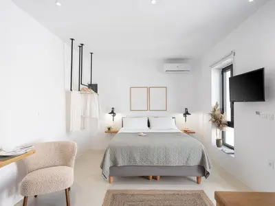 a white bedroom with a bed and two chairs at Lithos Retreat 2(ΛΙTHOS Retreat) in Kolymvari