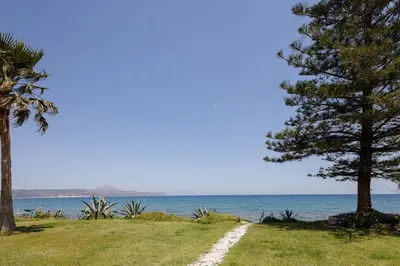 a road leading to the beach with trees and the ocean at Adelphes Beachfront Apartment with direct connection to the beach in Chania Town