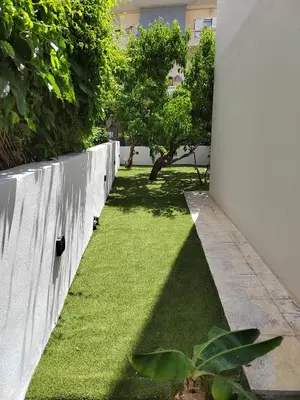 a garden with green grass next to a white wall at Callisto in Chania Town