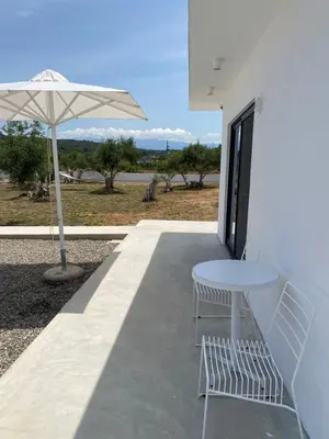 a white table and chairs and an umbrella on a patio at Lefko Apartments in Tavronitis
