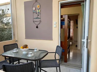 a table with chairs and a table with cups on it at Kissamos Nice Apartment2 in Kissamos