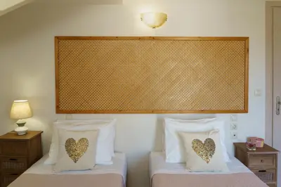 a bedroom with two beds and a large headboard at Arch Houses - Nature Escape with Shared Pool in Spiliá