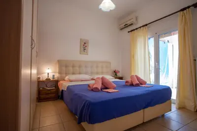 a bedroom with a bed with blue sheets and a window at Villa Festos in Voúvai