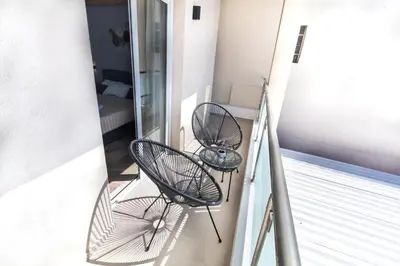 two chairs sitting on the balcony of a building at Queen Mary Beachfront Studios in Agia Marina Nea Kydonias