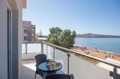 a balcony with a table and chairs and a beach at Queen Mary Beachfront Studios in Agia Marina Nea Kydonias