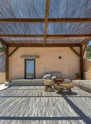 a patio with a large roof with a bench and a table at Kaliva Residence in Kalyves
