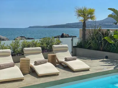 a group of lounge chairs next to a swimming pool at Kaliva Residence in Kalyves