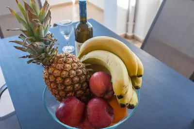 a bowl of fruit on a table with a bottle of wine at Hillside Seaview Apartment in Stalos