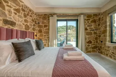 a large bed in a room with a stone wall at White House Boutique in Koukounará