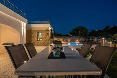 a dining table and chairs on a patio at night at White House Boutique in Koukounará
