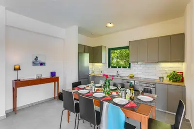 a kitchen with a table with chairs and a dining room at Villa Ilos by Villa Plus in Pírgos Psilonérou