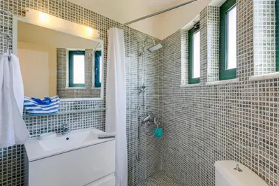 a bathroom with a shower and a sink and a mirror at Villa Ilos by Villa Plus in Pírgos Psilonérou