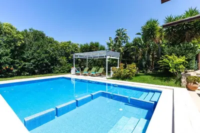 a swimming pool with blue water in a backyard at Villa Liostasi by Villa Plus in Agia Marina Nea Kydonias