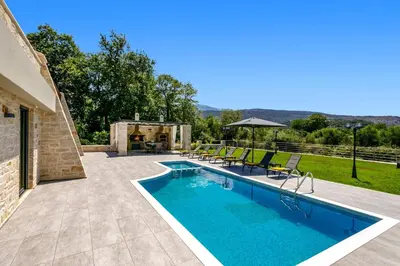 a swimming pool with chairs and a patio at Villa Potami Angela by Villa Plus in Stílos